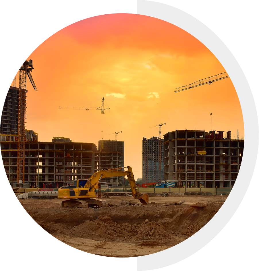 Construction site with an excavator and multiple cranes under a vibrant orange sky. Partially obscured by a white circular overlay on the right.