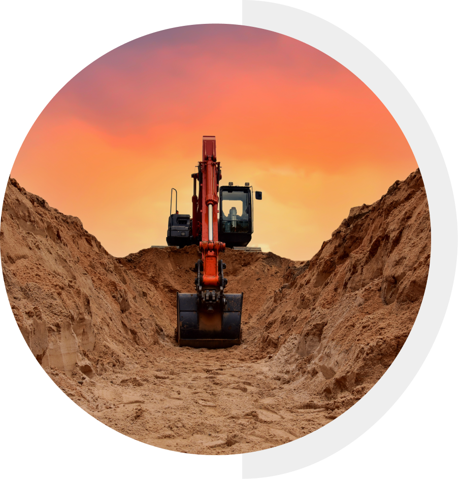 A construction excavator digging between mounds of dirt against a vibrant sunset sky.